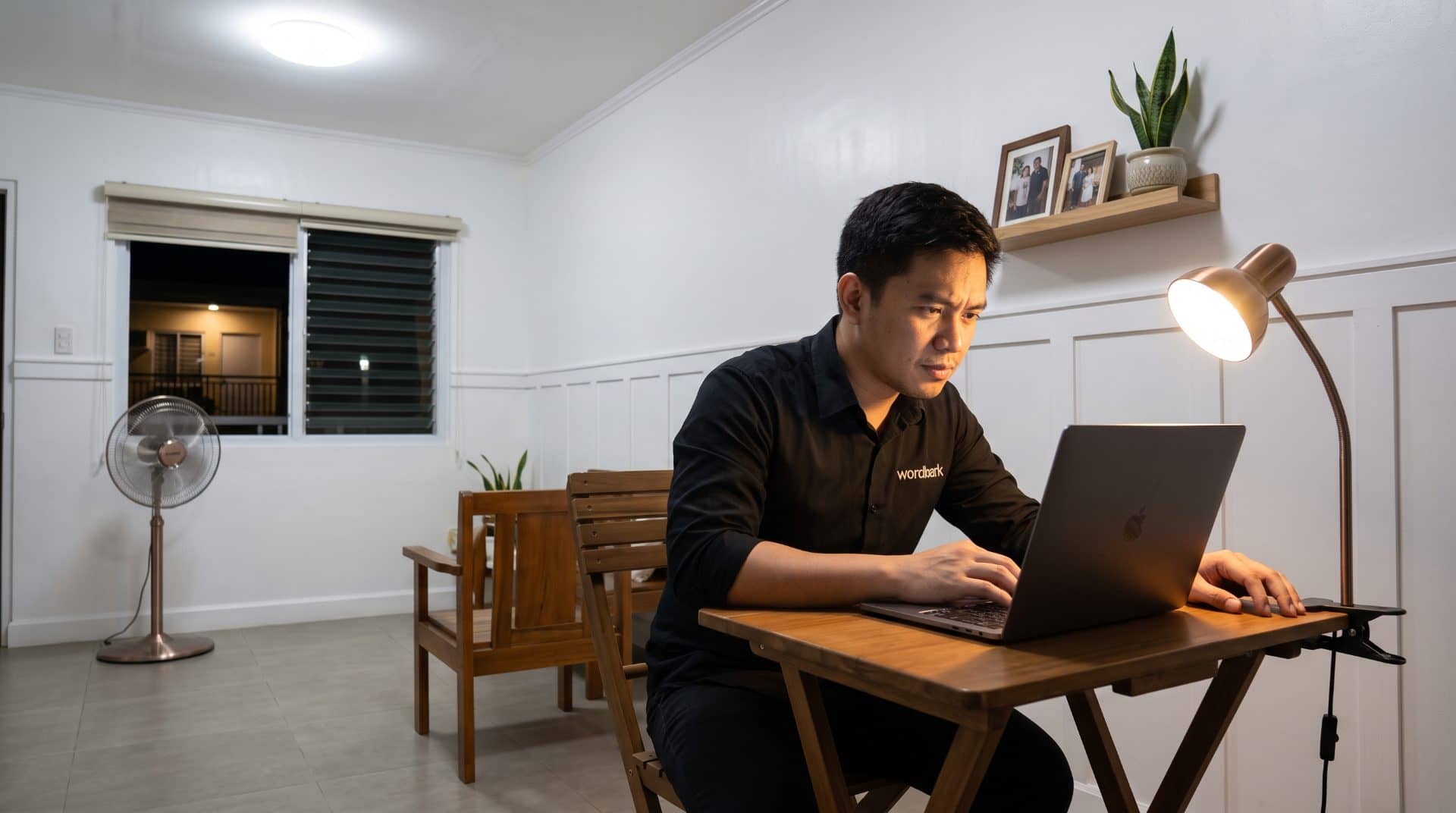 A Filipino man leaning forward slightly in a modest home office in Iloilo.